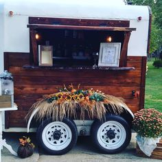 an old trailer converted into a bar with flowers on the front and side wheel rims