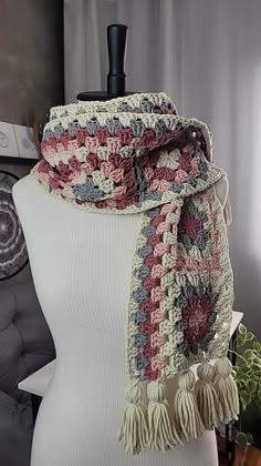 a white mannequin wearing a multicolored crocheted scarf