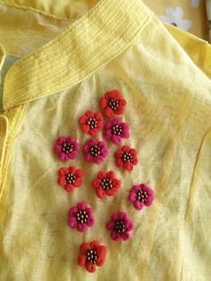 red and pink flowers are placed on a yellow shirt with black dots in the center