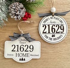 two personalized christmas ornament hanging on a wooden table next to pine cones