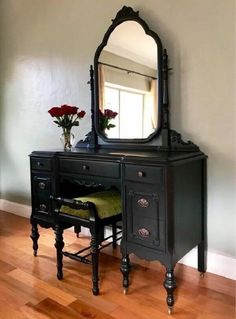 a black vanity with mirror and stool on wooden floor