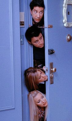 three people peeking out from behind a door with the doors open and one person looking at them