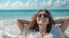 a woman wearing sunglasses laying on the beach