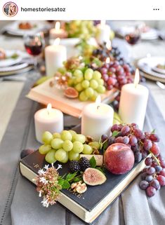 a table topped with plates and candles filled with fruit