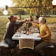 a group of people sitting around a table with food and wine glasses in their hands