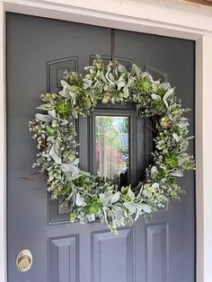 a wreath hanging on the front door of a house with a mirror in it's center