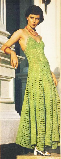 a woman in a green crocheted dress is standing on the steps with her hand on her hip