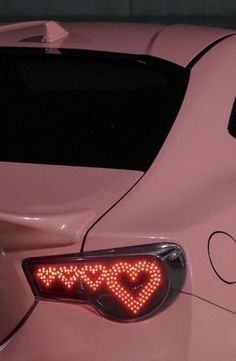 a pink car with the word love written on it's taillight and heart shaped lights