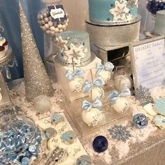 a table topped with lots of cakes and desserts covered in snowflake frosting