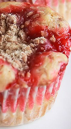 a muffin with crumbs and strawberries in it sitting on a plate