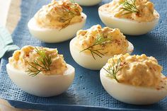 deviled eggs with dill on top are sitting on a blue towel and ready to be eaten