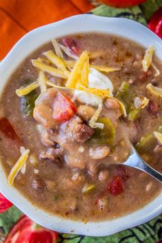 a white bowl filled with chili and cheese soup on top of a colorful table cloth