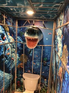 there is a toilet in the bathroom with a shark head on it's wall