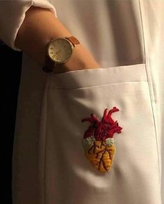 a close up of a person wearing a wrist watch with an embroidered heart on it