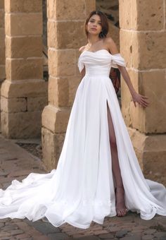 a woman wearing a white dress standing in front of an old stone building with columns