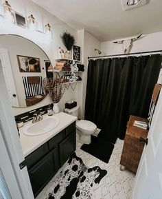 a bathroom with a black and white rug on the floor next to a shower curtain