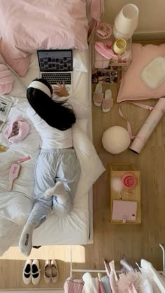 an overhead view of a person laying in bed with their laptop and other items on the floor