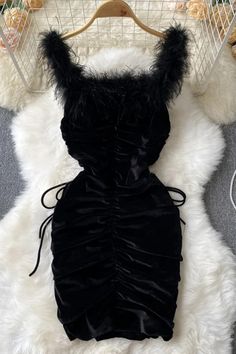 a black dress on a hanger in front of a white fur rug and teddy bear