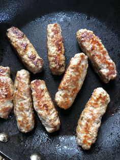 sausages are cooking in a skillet on the stove