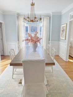 a dining room table with white chairs and a chandelier