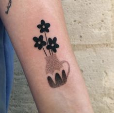 a person with a tattoo on their arm holding a coffee mug and flowers in it