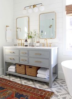 a bathroom with two sinks and mirrors on the wall above it is decorated in white and gold