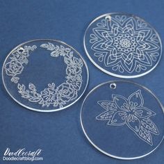 three etched glass ornaments on a blue background