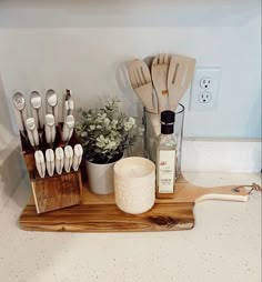 kitchen utensils are sitting on a cutting board in the middle of a counter