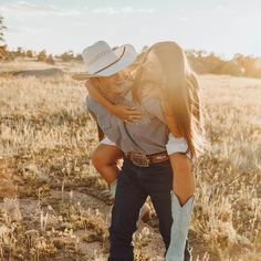 a man and woman hug in the middle of a field