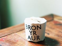 a brown wooden table topped with a white cup filled with liquid and writing on it