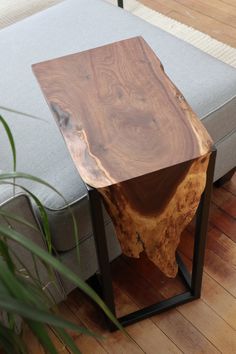 a wooden table sitting on top of a metal frame next to a couch and potted plant