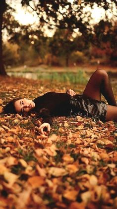 a woman laying on the ground in leaves