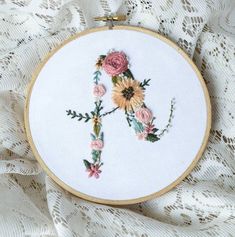 a cross stitched with flowers on top of a white lace covered table cloth,