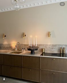 a kitchen with two sinks and candles on the counter top next to each other in front of a white wall