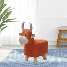 a toy cow sitting on top of a blue rug next to a chair and potted plant