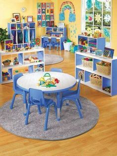 a child's playroom with blue chairs, tables and shelves filled with toys