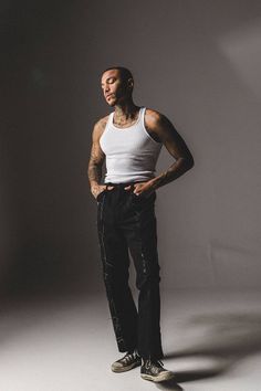 a man in white tank top and black pants standing with his hands on his hips