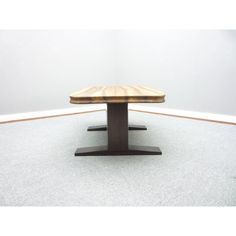 a wooden table sitting on top of a white carpeted floor next to a wall