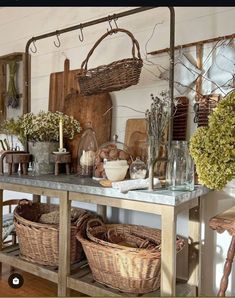 a table topped with baskets filled with flowers and other items next to a wall mounted mirror