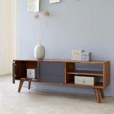 a vase sitting on top of a wooden shelf next to a wall with pictures above it