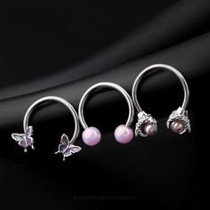 three different types of nose rings with butterflies on them, one is pink and the other is