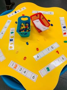 a yellow table topped with lots of toys and numbers on it's surface next to a basket