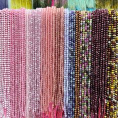 many beads are hanging on the wall in different colors and sizes, including pinks, purples, yellows, and green