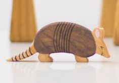 a small wooden toy armadile on a white surface