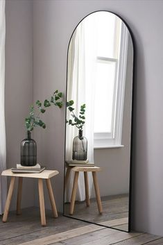 a mirror sitting next to a table with two vases on it's sides