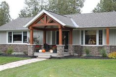 a house that is in the grass with flowers on the front porch and two windows