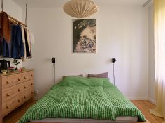 a bedroom with a bed, dresser and hanging clothes on the wall above it's headboard