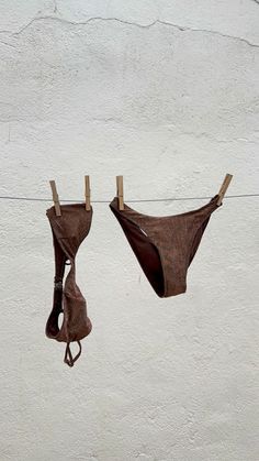 two bikinis hanging on clothesline with no strings attached to the line, against a white wall