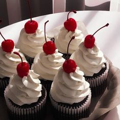 cupcakes with white frosting and cherries on top