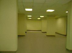 an empty room with white walls and lights on either side of the wall is a long hallway